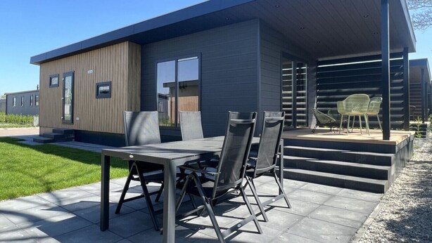 Una casa moderna con un patio que cuenta con una mesa y sillas.
