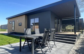 Une maison moderne dotée d’un patio comprenant une table et des chaises.