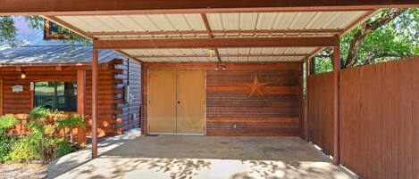 A covered outdoor area with a wooden fence, a star decoration, and a building with a metal roof.