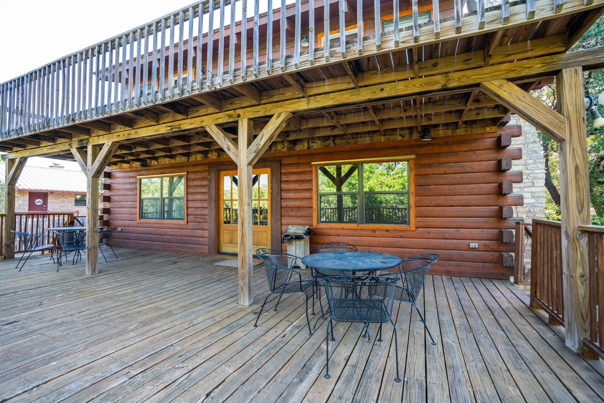 A wooden cabin with a deck, a dining table, and chairs.