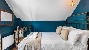 A bedroom with a bed, a nightstand, a mirror, and a hanging light fixture.