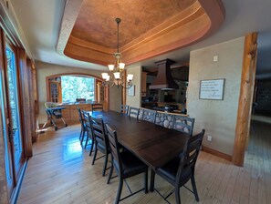 A dining area with a long table, chairs, and a chandelier.