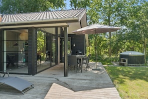 A modern outdoor deck with a dining area, a covered seating area, and a small shed.