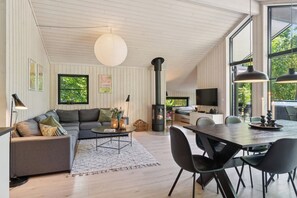 Ein modernes Wohnzimmer mit einer Couch, einem Esstisch und einem großen Fenster.