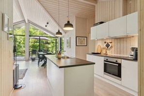 Eine moderne Küche mit Kochinsel, integriertem Backofen und Pendelleuchten.