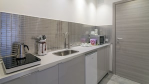 A modern kitchen with a stainless steel sink, a kettle, a coffee machine, and a microwave. - JOIVY Cosy & Modern Apartments near Milan Central Station (Milan)