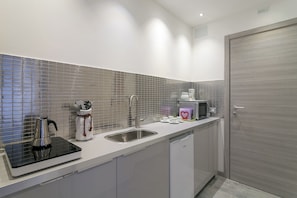 A modern kitchen with a stainless steel sink, a kettle, a coffee machine, and a microwave. - JOIVY Cosy & Modern Apartments near Milan Central Station (Milan)