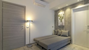 A modern bedroom with a bed, a bedside lamp, a wall-mounted air conditioner, and a door. - JOIVY Cosy & Modern Apartments near Milan Central Station (Milan)