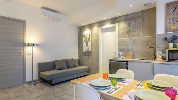 A modern living room with a sofa, dining table, and kitchen area. - JOIVY Cosy & Modern Apartments near Milan Central Station (Milan)