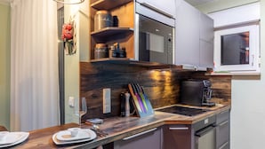 Une cuisine moderne équipée d’un four à micro-ondes, d’une machine à café et d’un plan de travail en bois.