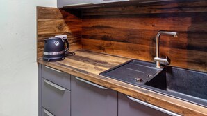 Une cuisine de taille réduite, avec un plan de travail en bois derrière l’évier, un seul évier et une machine à café.