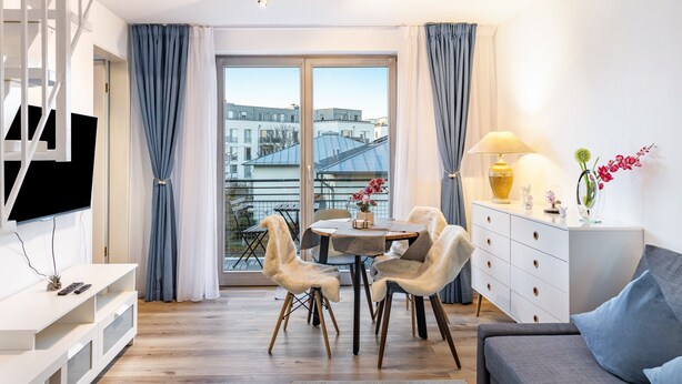 A modern living room with a TV, a dining table with chairs, a sofa, a lamp, and a vase with flowers. - Maisonette Apartment near BER Airport, Schönefeld – 2 Bedrooms, Parking, Wi-Fi (Schönefeld)