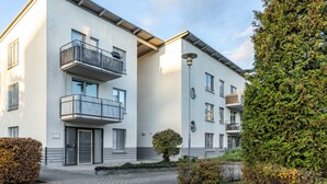 A modern multi-story residential building with balconies, a paved courtyard, and a well-maintained hedge. - Maisonette Apartment near BER Airport, Schönefeld – 2 Bedrooms, Parking, Wi-Fi (Schönefeld)