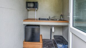 A compact kitchen with a microwave, sink, and storage space. - The Owl Pod - UK50070 (Welshpool)