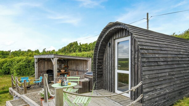 A rustic wooden cabin with a deck, outdoor seating, and a grill area. - The Owl Pod - UK50070 (Welshpool)
