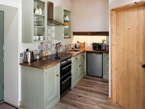 A compact kitchen with a sink, stove, microwave, and dishwasher. - The Calving Barn - UK49679 (Bratton Fleming)