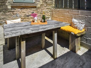 A rustic wooden table with a bench, a bottle of champagne, and a vase of flowers. - The Calving Barn - UK49679 (Bratton Fleming)