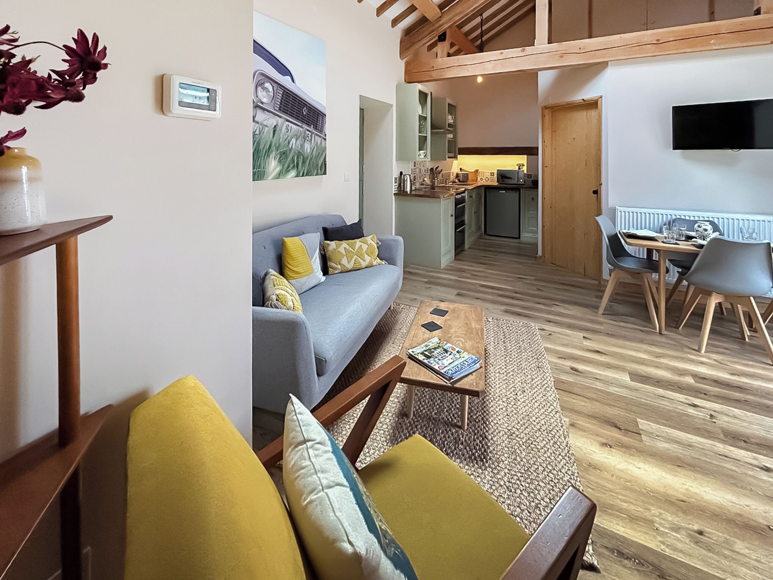 A modern living room with a sofa, coffee table, and a dining area with chairs and a table.