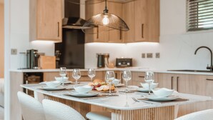 Una cocina moderna con armarios de madera, una isla central con asientos e iluminación colgante.