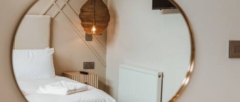 A bedroom with a bed, bedside table, lamp, and a radiator.