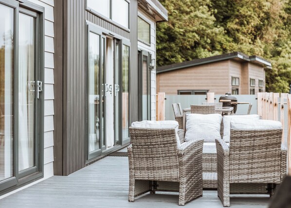 A covered outdoor seating area with wicker furniture and a wooden deck.