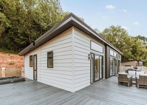 Ein modernes Haus mit Terrasse, großen Fenstern und einem Whirlpool.