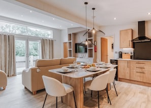 Un comedor moderno con una mesa de madera, sillas blancas y una lámpara colgante.