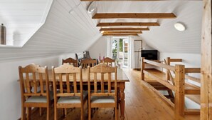 Ein Holzespeisezimmer mit Stühlen, einem Fernseher und einer Bank in einem Raum mit weißen Wänden und Holzbalken.