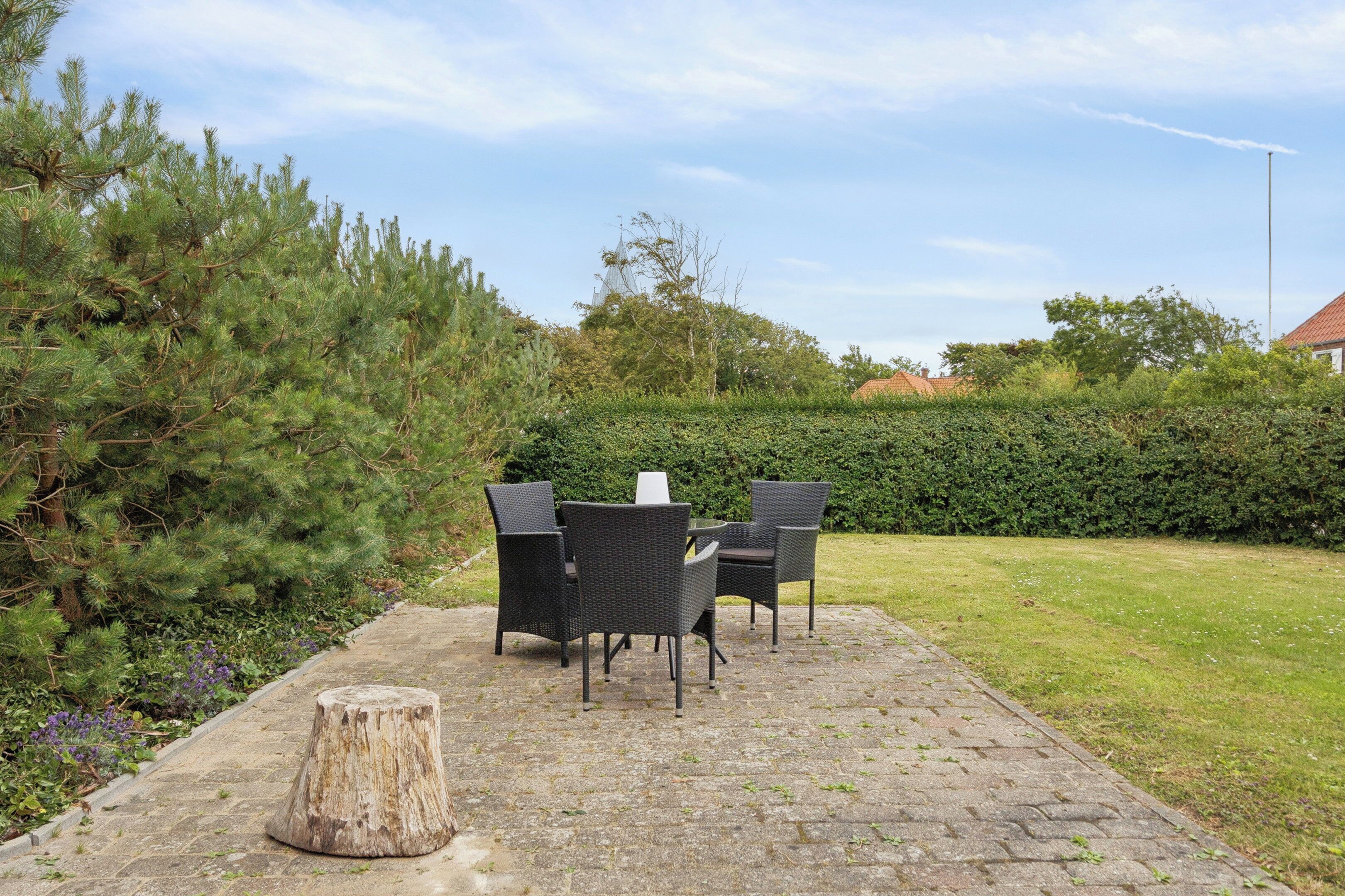 Un patio al aire libre con mobiliario de mimbre, una mesa de piedra y un tocón de árbol.
