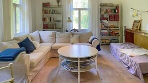 A cozy living room with a beige sofa, a round coffee table, and a bookshelf filled with books and decorative items. - Stunning home in Skillingaryd with sauna (Skillingaryd)
