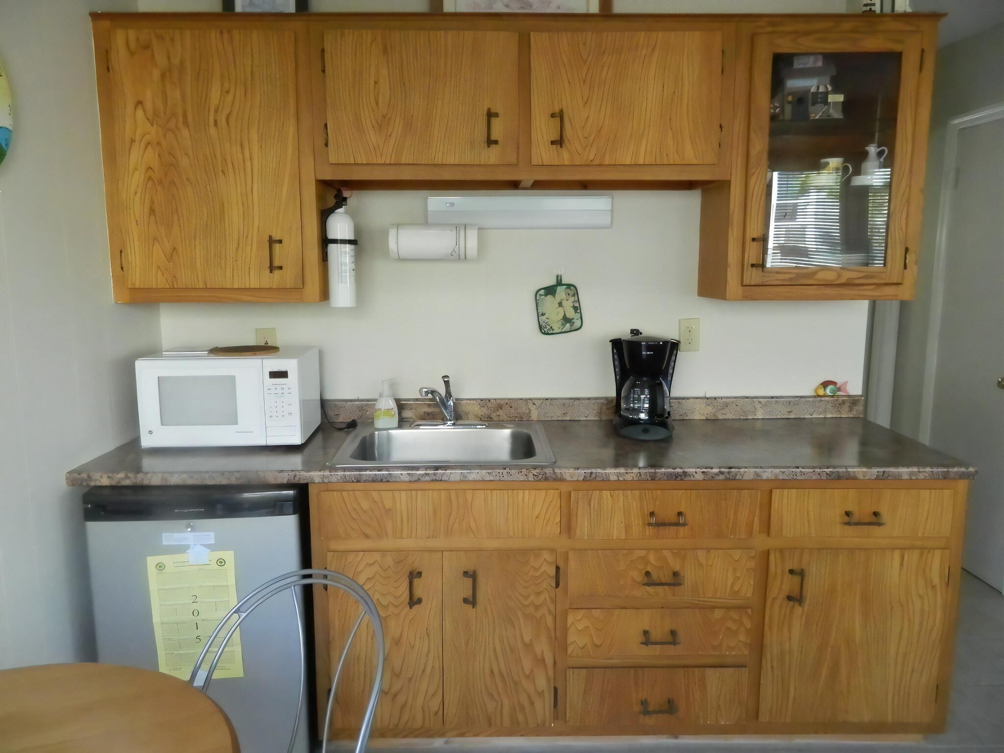 A kitchen with wooden cabinets, a microwave, a coffee maker, and a sink.