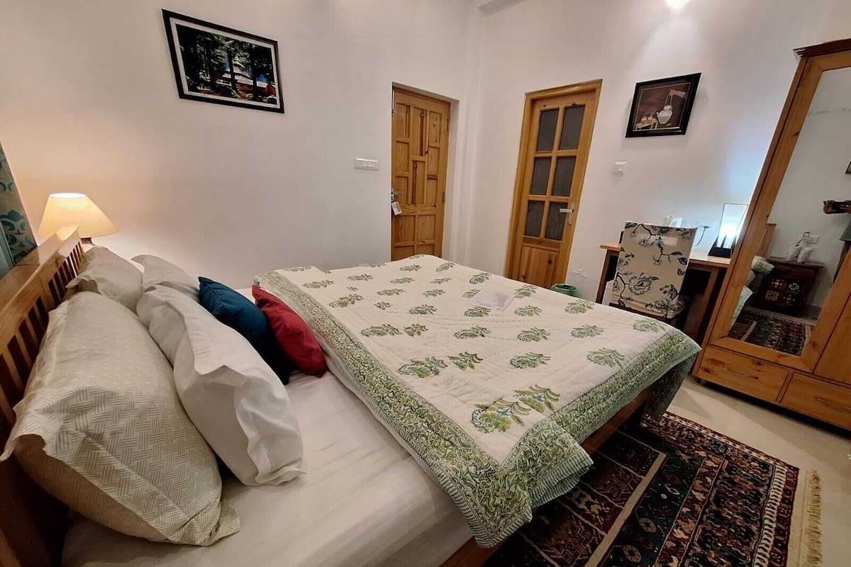 A bedroom with a bed, a wooden wardrobe, and a chair.