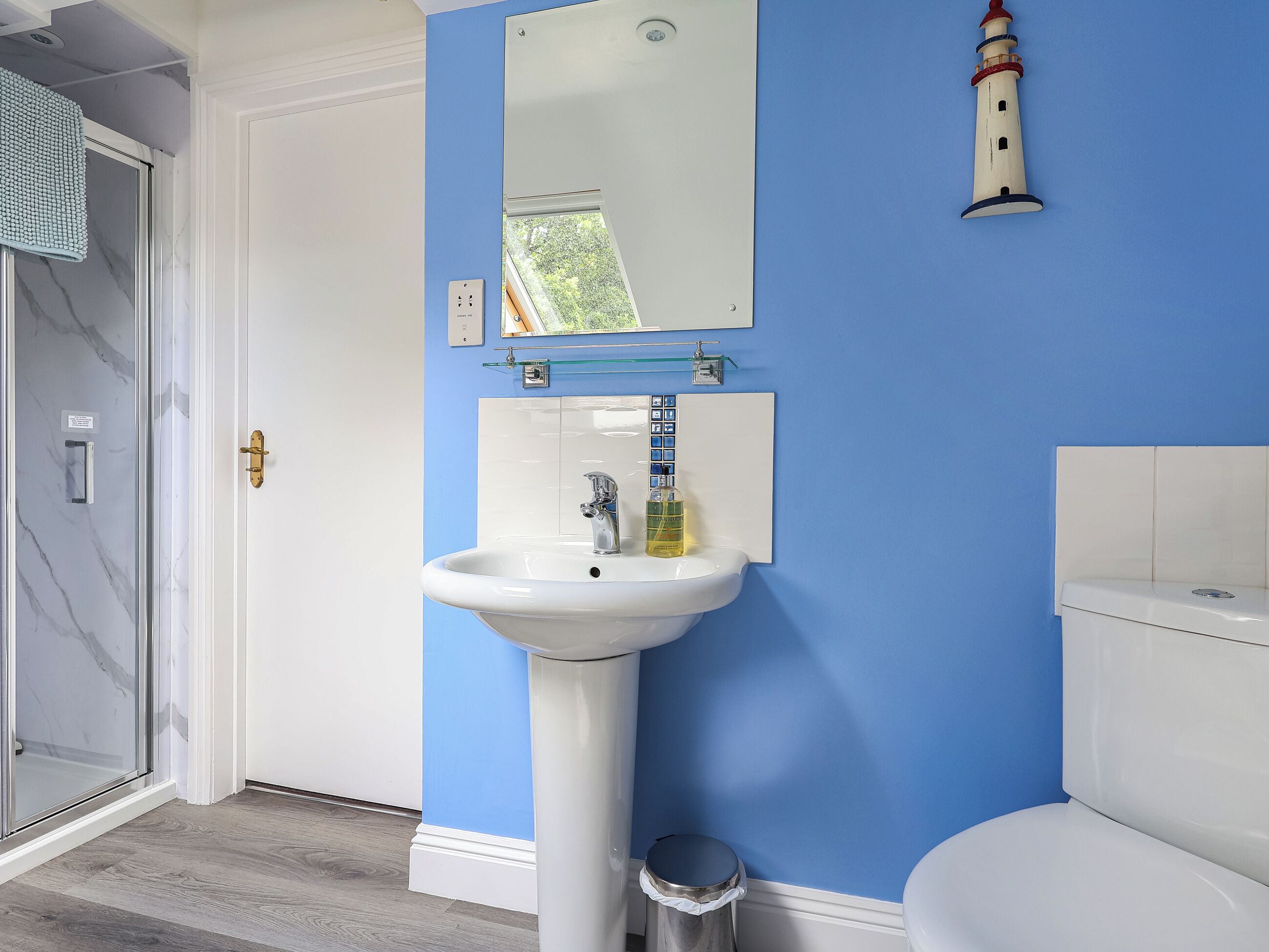 Un baño con un lavabo blanco, paredes azules, un espejo y un inodoro.