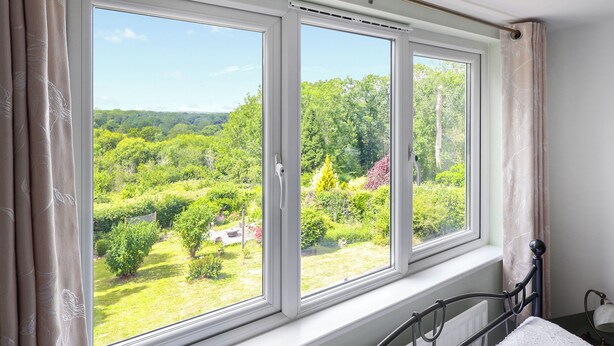 A room with a large window overlooking a lush garden and forested area.