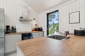 Una cocina moderna con armarios de madera, horno empotrado y un amplio ventanal.