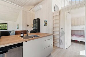 A compact kitchen with a dishwasher, a wooden countertop, and a built-in cabinet.