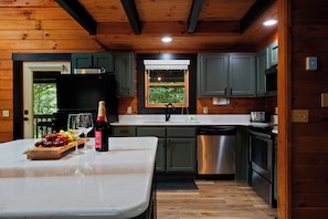 Una cocina con interior de madera, lavavajillas de acero inoxidable y horno empotrado.