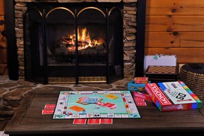 Et Monopoly-spil stillet frem på et træbord med en pejs i baggrunden.