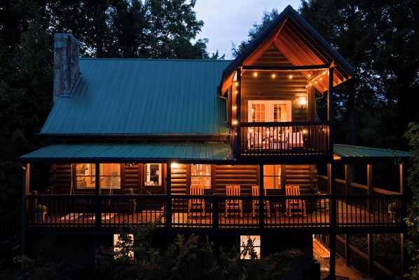 A two-story log cabin with a balcony and multiple windows.