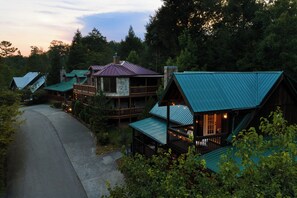 A row of cabins with metal roofs, surrounded by trees and a paved path.