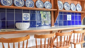 A kitchen with wooden cabinets, blue and white tiles, and a white bowl on the counter. - 2 bedroom accommodation in Camelford (Camelford)