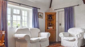 A room with two white armchairs, a wooden cabinet, and a patterned rug. - 2 bedroom accommodation in Camelford (Camelford)