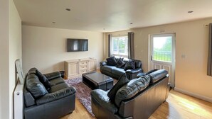A modern living room with a flat-screen TV, two sofas, a coffee table, and a cabinet. - 3 bedroom accommodation in Brigg (Brigg)