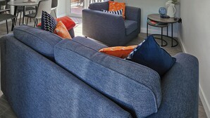Una sala moderna con un sofá, un sillón y una pequeña mesa.