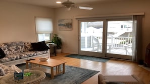 A living room with a sofa, coffee table, and a view of a balcony with outdoor furniture.