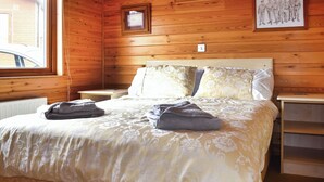 A wooden-paneled bedroom with a bed, two nightstands, and a framed picture on the wall. - 2 bedroom accommodation in Ilfracombe (Ilfracombe)