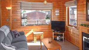 A cozy cabin interior with a sofa, a coffee table, a TV, and a fireplace. - 2 bedroom accommodation in Ilfracombe (Ilfracombe)