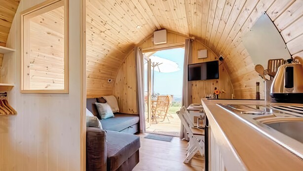 Un interior acogedor de madera con un sofá, un televisor y una zona de cocina.