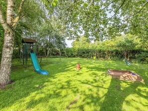Ein Spielplatz mit Rutsche, Schaukeln und einer Kletterkonstruktion.