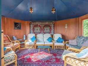 Ein Zimmer mit Korbmöbeln, gemusterten Teppichen und hängenden Laternen.
